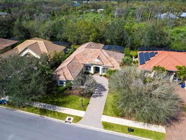 Stunning aerial view of a single-Gathering home with a tile roof, lush landscaping, and a paver driveway at 7533 Trillium Blvd, Sarasota, FL 34241