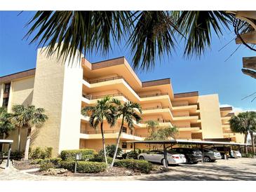 Multi-story condo building with palm trees, landscaping and covered parking spaces at 8779 Midnight Pass Rd # 406H, Sarasota, FL 34242