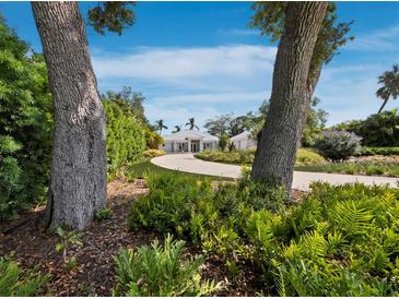 Landscaped front yard leading to a modern home with a circular driveway and lush greenery at 1909 Field Rd, Sarasota, FL 34231