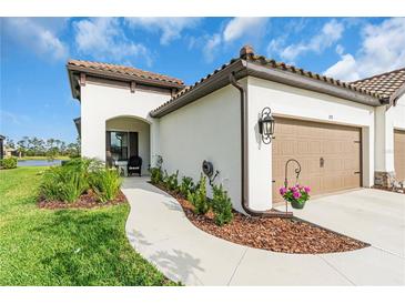 Charming home featuring a tile roof, stucco exterior, beautiful landscaping, and a two-car garage at 253 Tracino Ter, Nokomis, FL 34275