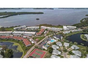 Stunning aerial view showcasing the waterfront community, pool, tennis courts, and lush landscaping at 4753 Independence Dr, Bradenton, FL 34210