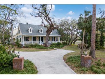 Charming yellow two-story home featuring a welcoming front porch and a long driveway at 4871 Hoyer Dr, Sarasota, FL 34241