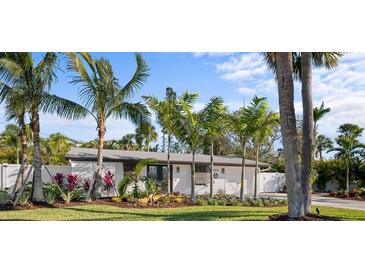 Inviting single-story home featuring lush tropical landscaping and a well-manicured lawn at 7701 Palm Dr, Holmes Beach, FL 34217