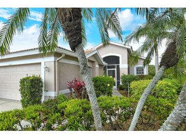 Beautiful home exterior with lush landscaping, including palm trees and colorful plants at 9411 Forest Hills Cir, Sarasota, FL 34238