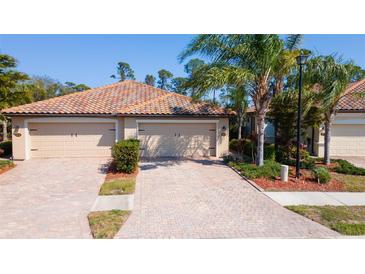 Charming villa with a brick driveway, two-car garage, and a beautifully landscaped front yard at 20186 Benissimo Dr, Venice, FL 34293