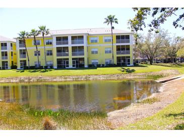Bright yellow condo complex with tall palm trees overlooking a scenic pond at 2060 Willow Hammock Cir # 201, Punta Gorda, FL 33983