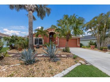 Charming single-story home with a beautiful, lush tropical landscaped front yard and a matching terracotta-colored exterior at 5227 Lansdowne Way, Palmetto, FL 34221