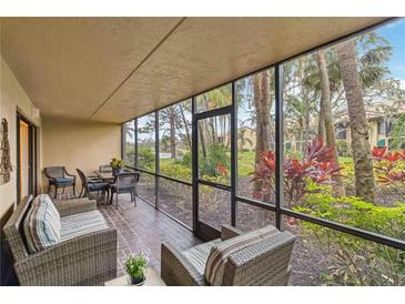 Screened-in patio with wicker furniture and a view of lush greenery and tropical plants at 5568 Ashton Lake Dr # 5568, Sarasota, FL 34231