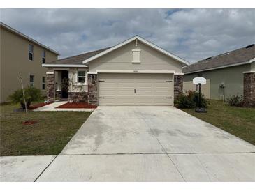 Beige single story home with a 2 car garage, stone accents and well maintained front yard at 5838 Elegant Orchid Way, Sarasota, FL 34232