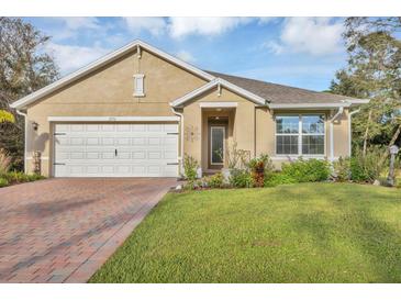 Charming single-story home featuring a manicured lawn, brick driveway, and attached two-car garage at 2756 Canoe Ln, North Port, FL 34286
