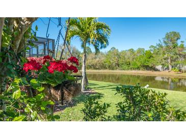 A beautifully landscaped backyard with a pond view and vibrant red hanging flowers adds charm to the outdoor space at 315 Londonderry Dr, Sarasota, FL 34240