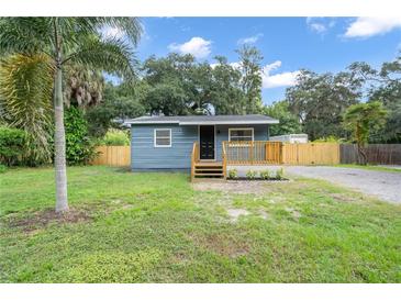 Charming cottage-style home featuring blue siding, a wood deck, and a spacious front yard at 3561 Elfers Pkwy, New Port Richey, FL 34655