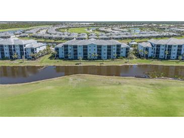 Aerial view of a light blue condo complex surrounded by lush green grass and a serene lake at 14061 Heritage Landing Blvd # 412, Punta Gorda, FL 33955
