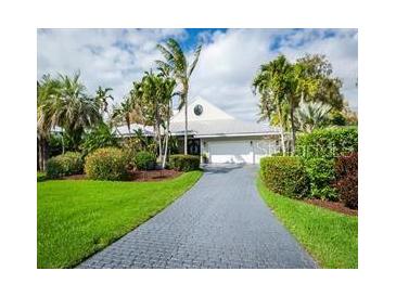 Charming single-story home featuring a paved driveway and lush tropical landscaping, creating a serene and inviting curb appeal at 1511 N Lake Shore Dr, Sarasota, FL 34231
