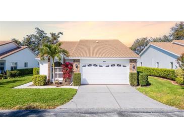 Charming home featuring a well-manicured lawn, tile roof, and an attached two-car garage at 5814 Garden Lakes Fern, Bradenton, FL 34203