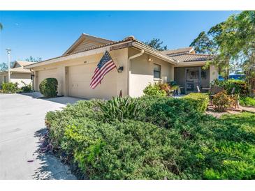 Charming single-story home featuring a well-manicured lawn, attached garage, and an American flag at 7183 Wood Creek Dr # 9, Sarasota, FL 34231