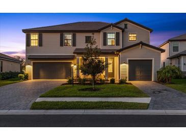 Charming two-story home with a well-manicured lawn, brick-paved driveway, and a two-car garage, enhancing curb appeal at 16455 Whale Grey Pl, Bradenton, FL 34211