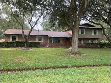 Charming two-story home with lush landscaping and mature trees on an expansive green lawn at 411 El Greco Dr, Brandon, FL 33511