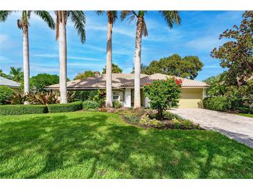 Beautiful home featuring a well-manicured lawn, mature trees, and colorful landscaping at 4852 Peregrine Point N Cir, Sarasota, FL 34231
