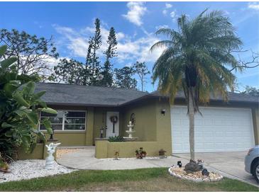 Charming single-story home featuring lush landscaping, a fountain, and a two-car garage at 5180 Guava Ter, Port Charlotte, FL 33981