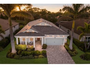 Beautiful single Gathering home with mature landscaping, brick driveway, and a two-car garage at 5557 Long Shore Loop, Sarasota, FL 34238