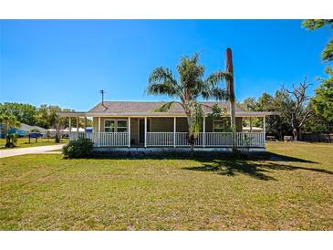 Charming single-story home featuring a cozy front porch, mature trees, and a well-maintained lawn at 5860 Brown Ln, Sarasota, FL 34232