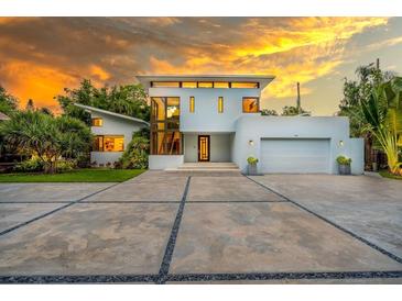 Contemporary two-story home featuring a clean facade, oversized windows, and an expansive concrete driveway at 587 47Th St, Sarasota, FL 34234