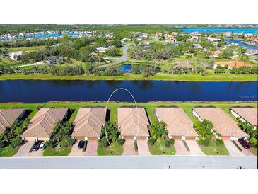 Aerial view of waterfront villas with tile roofs and lush landscaping near a tranquil canal at 6638 Willowshire Way, Bradenton, FL 34212