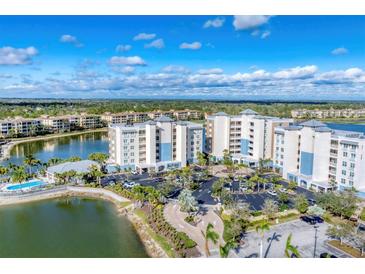 Stunning aerial view of a lakeside condominium complex featuring lush landscaping and ample parking at 10520 Boardwalk Loop # 503, Bradenton, FL 34202