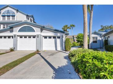 Charming coastal-style home with a well-manicured lawn, multi car garage, and a neatly paved driveway on a sunny day at 1239 Siesta Bayside Dr # 1239C, Sarasota, FL 34242