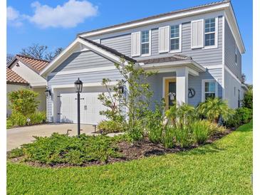 Charming two-story home showcasing a manicured lawn, inviting curb appeal, and a two-car garage at 12959 Seasong Ter, Bradenton, FL 34211