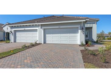 Charming home exterior featuring a brick driveway leading to a two-car garage with a well-manicured lawn at 18137 Franklin Park Ct, Venice, FL 34293