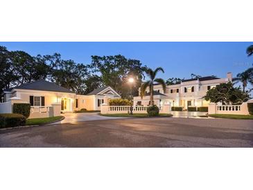 Stately home with lush landscaping, circular drive, and elegant architectural details at twilight at 236 Saint James Park, Osprey, FL 34229