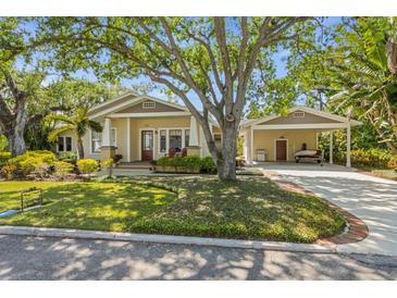 Charming bungalow featuring a well-maintained lawn, beautiful shade tree, and covered carport at 325 12Th W Ave, Palmetto, FL 34221