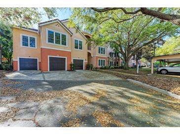 Two-story condo featuring attached garages, colorful stucco, and lush trees at 4110 Central Sarasota Pkwy # 123, Sarasota, FL 34238