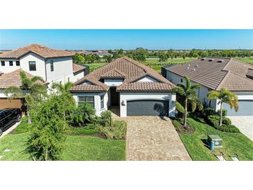 Beautiful home with a well-manicured lawn, brick driveway, and tropical landscaping, located on a golf course at 5817 Brandon Run, Bradenton, FL 34211