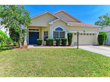 Charming home featuring a well-manicured lawn, a blue door with wreaths, and mature landscaping at 6415 Fetterbush Ln, Lakewood Ranch, FL 34202