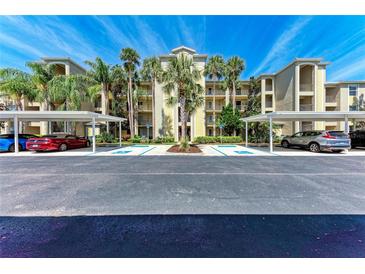 Beautiful condo building with covered parking surrounded by manicured landscaping and tall palm trees at 7803 Grand Estuary Trl # 303, Bradenton, FL 34212
