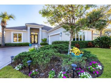 Landscaped front yard with colorful flowers and mature trees, creating a welcoming curb appeal at 8610 51St E Ter, Bradenton, FL 34211