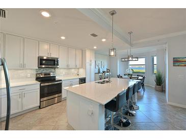 Modern kitchen featuring stainless steel appliances, a large island with seating, and bright, white cabinetry at 1020 Tidewater Shores Loop # 107, Bradenton, FL 34208