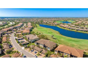 Expansive aerial view overlooking the condo community, scenic golf course, and serene lake at 13719 Messina Loop # 101, Lakewood Ranch, FL 34211