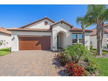 Beautiful single-story home with a tile roof, paver driveway, and lush tropical landscaping at 17216 Star Banks St, Wimauma, FL 33598