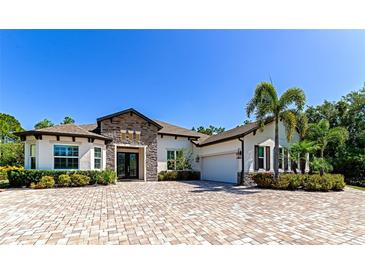 Stunning exterior of home with stone accents, lush landscaping, and brick driveway at 22209 Deer Pointe Xing, Bradenton, FL 34202
