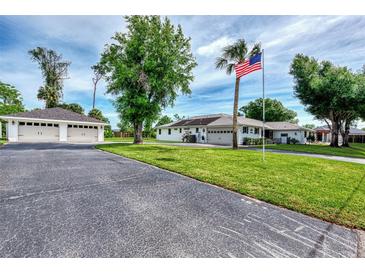 Spacious, well-maintained property featuring a lush lawn, mature trees, a detached garage, and an American flag at 3514 Laslo Ave, North Port, FL 34287