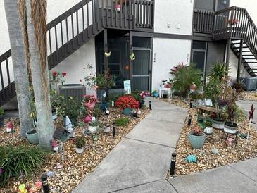 Condominium exterior with multiple plants, flowers, and garden decorations near the walkway at 3784 59Th W Ave # 3784, Bradenton, FL 34210