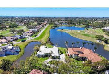 Stunning aerial view of a luxury home on a golf course with lake and lush landscaping at 4002 Las Palmas Way, Sarasota, FL 34238
