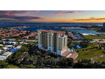Stunning aerial view of a waterfront condominium building with red tile roof and picturesque harbor views at sunset at 501 Haben Blvd # 202, Palmetto, FL 34221