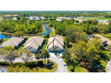 An aerial view of a home with a tile roof, tropical landscaping, and a serene waterway in the background at 7004 Old Tabby Cir, Lakewood Ranch, FL 34202