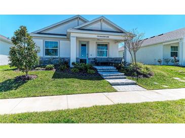 Charming single-story home with a manicured lawn, stone accents, and welcoming front porch with outdoor seating at 7712 Saloon Ln, Sarasota, FL 34240