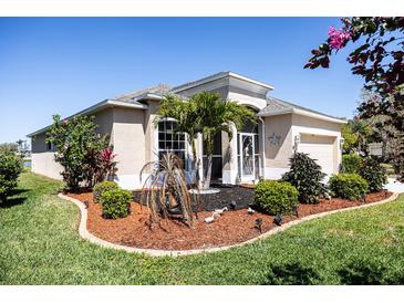 Charming home with a well-manicured lawn and landscaped garden featuring tropical plants and mulch at 8859 Founders Cir, Palmetto, FL 34221